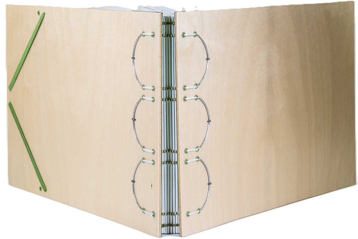 Sketchbook, using a "bound on cords" structure with white leather cords and green thread; laminated wood covers; 90# drawing paper; hand-hammered metal structural supports; green elastic closure.
