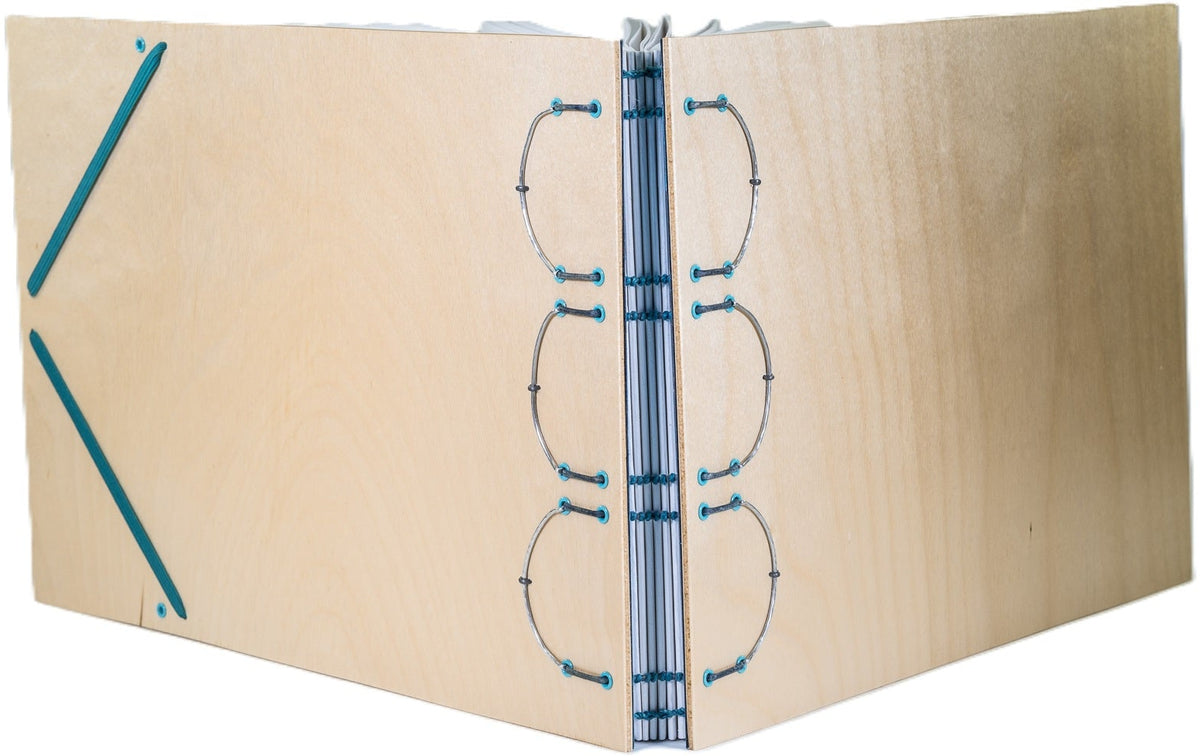 Sketchbook, using a "bound on cords" structure with brown leather cords and teal thread; laminated wood covers; 90# drawing paper; hand-hammered metal structural supports; teal elastic closure.