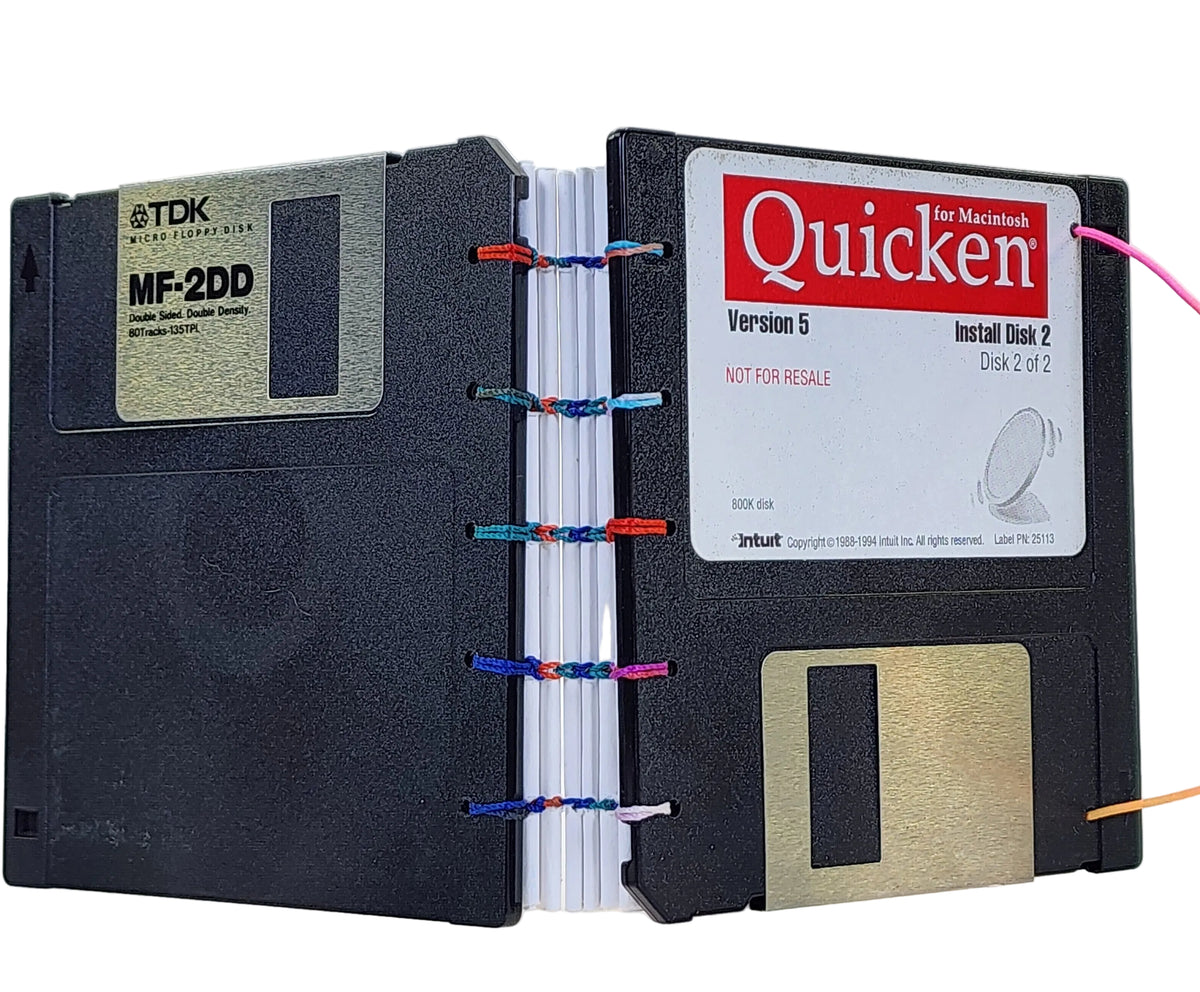 A novelty book made black floppy disk covers, bound with colorful thread, showing vintage disk labels including TDK MF-2DD and Quicken Version 5.