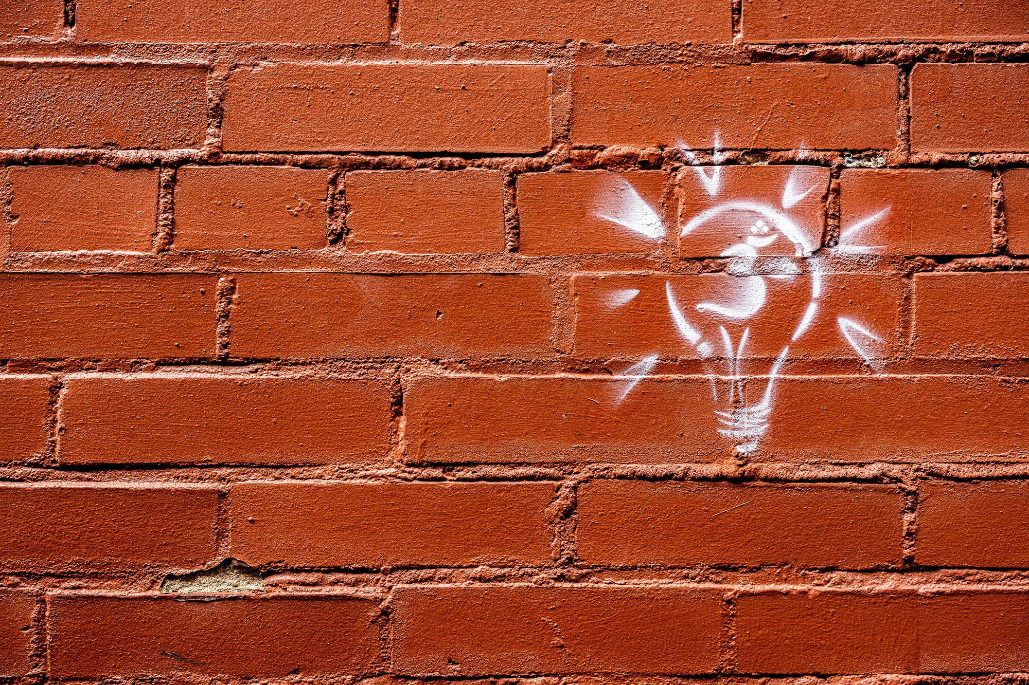Light bulb graffiti on a red brick wall; photographer Rick Graves