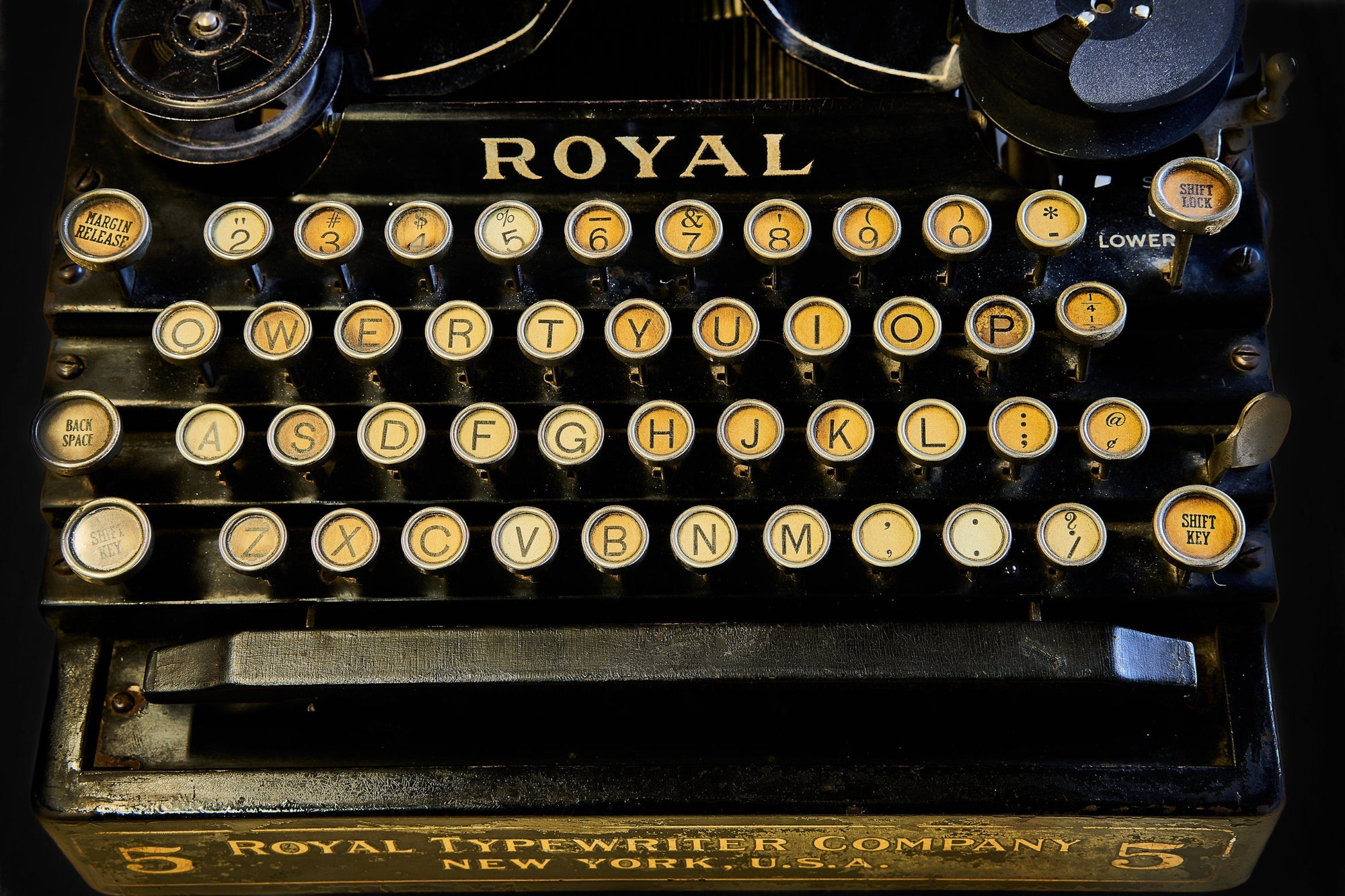 Close-up of the keyboard a vintage black Royal Typewriter No. 5 with round keys in various shades of cream to tan.