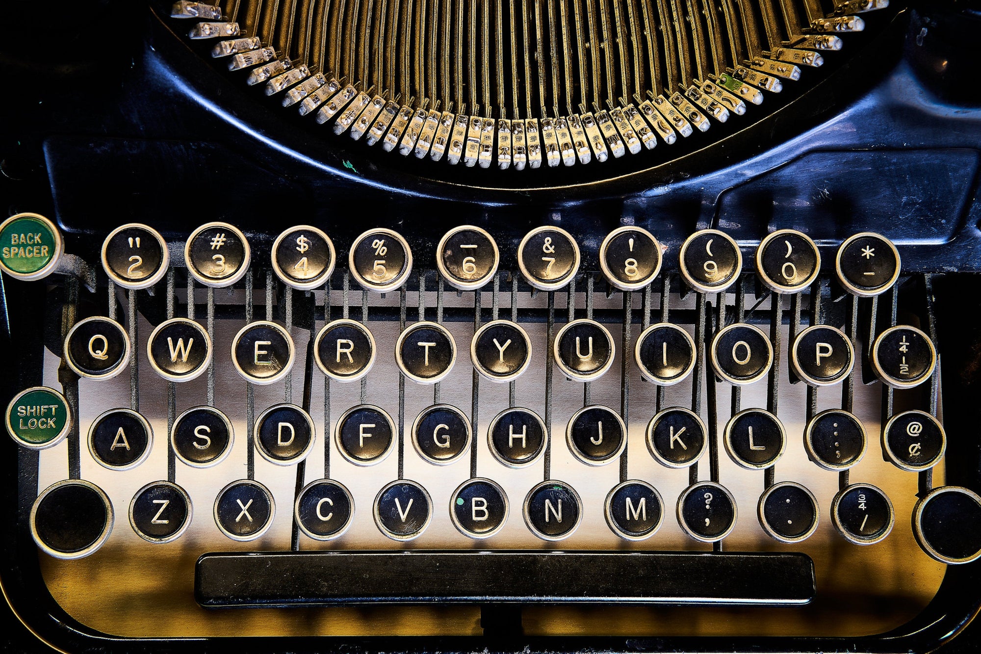 Back-lit close-up of a vintage typewriter keyboard with round black keys.