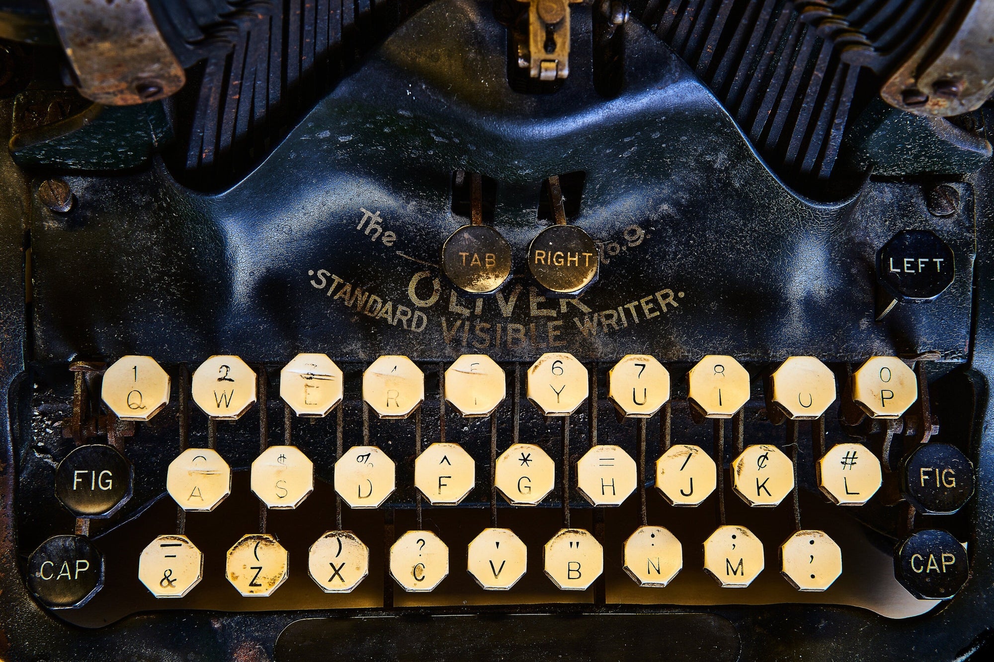 Close-up of a vintage black typewriter with cream-color eight-sided keys. Model: Oliver Standard Visible Writer branding.