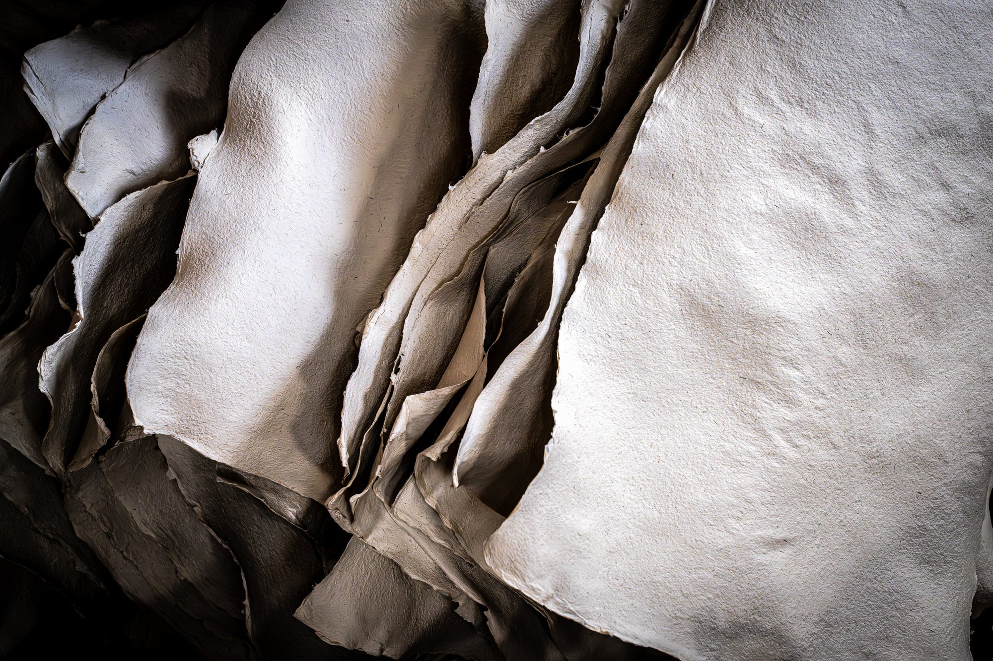 Sepia-toned close-up of a chaotic pile of handmade paper. Photographer Rick Graves
