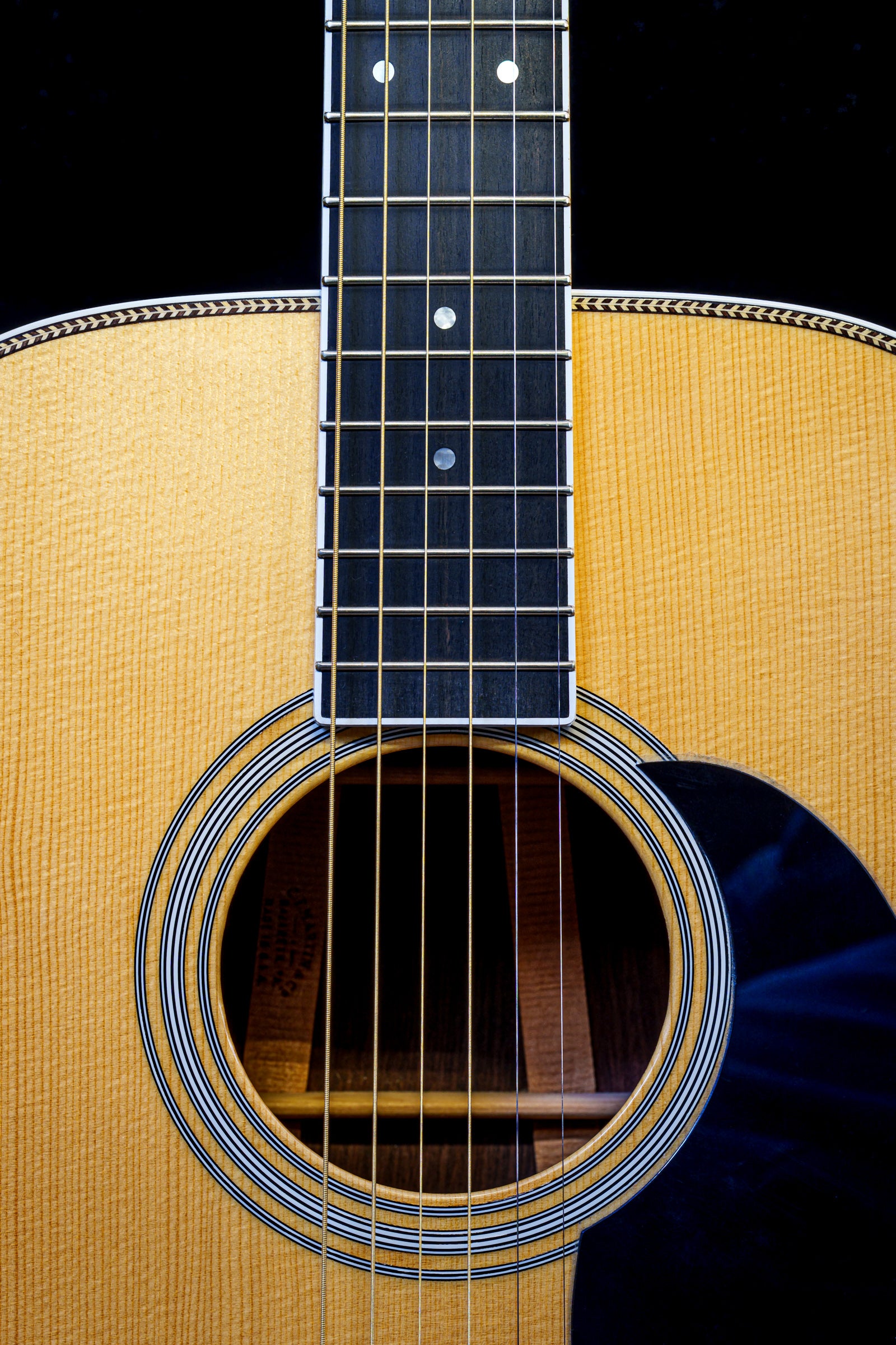 Close-up of a Martin acoustic guitar's soundhole and fretboard against a black background