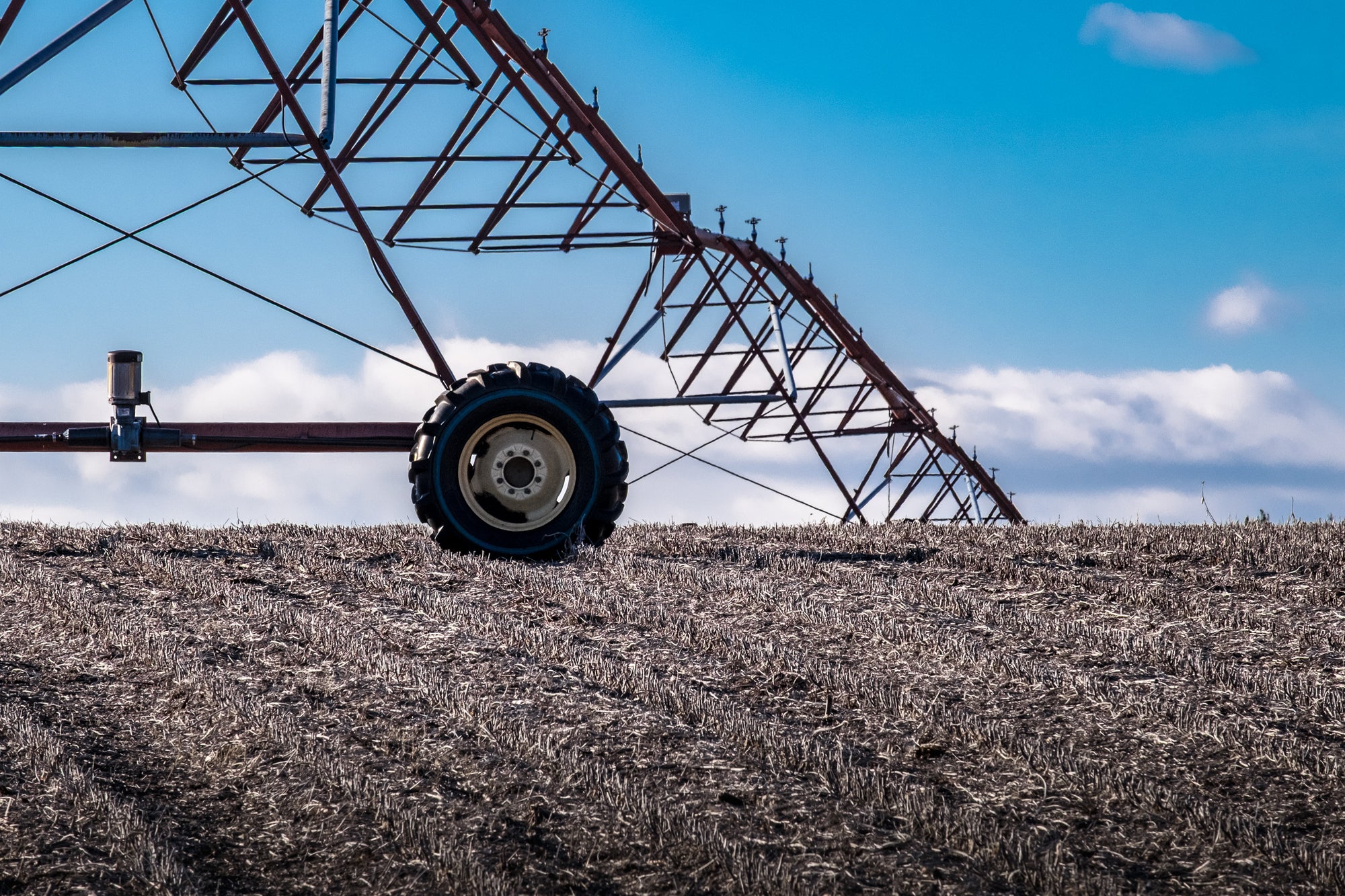 Agricultural sprinkler system on a field with a blue sky and clouds in the background; photographer Rick Graves