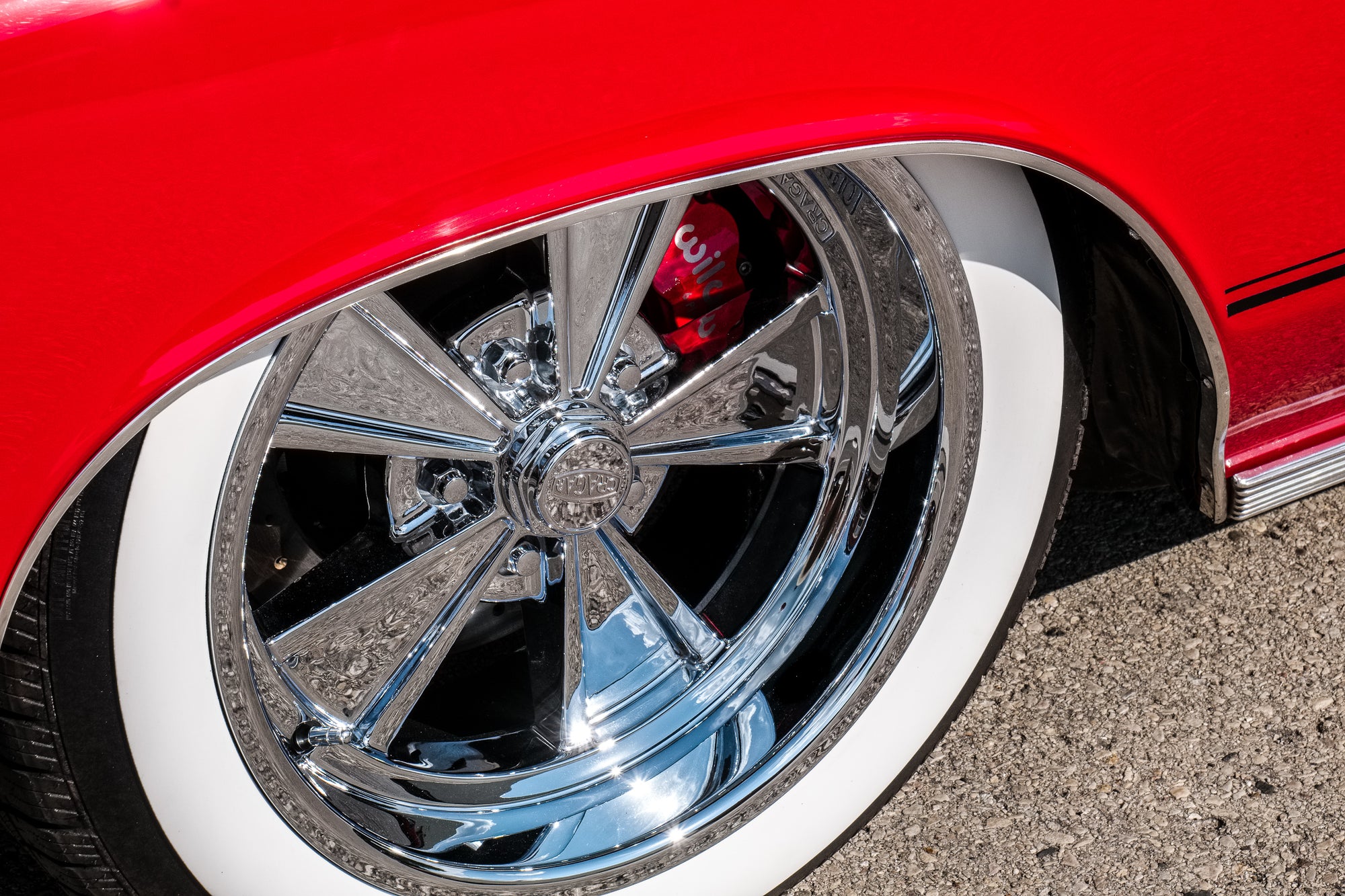 Close-up of a classic red car with chrome wheel and white wall tire on asphalt. Photographer Rick Graves