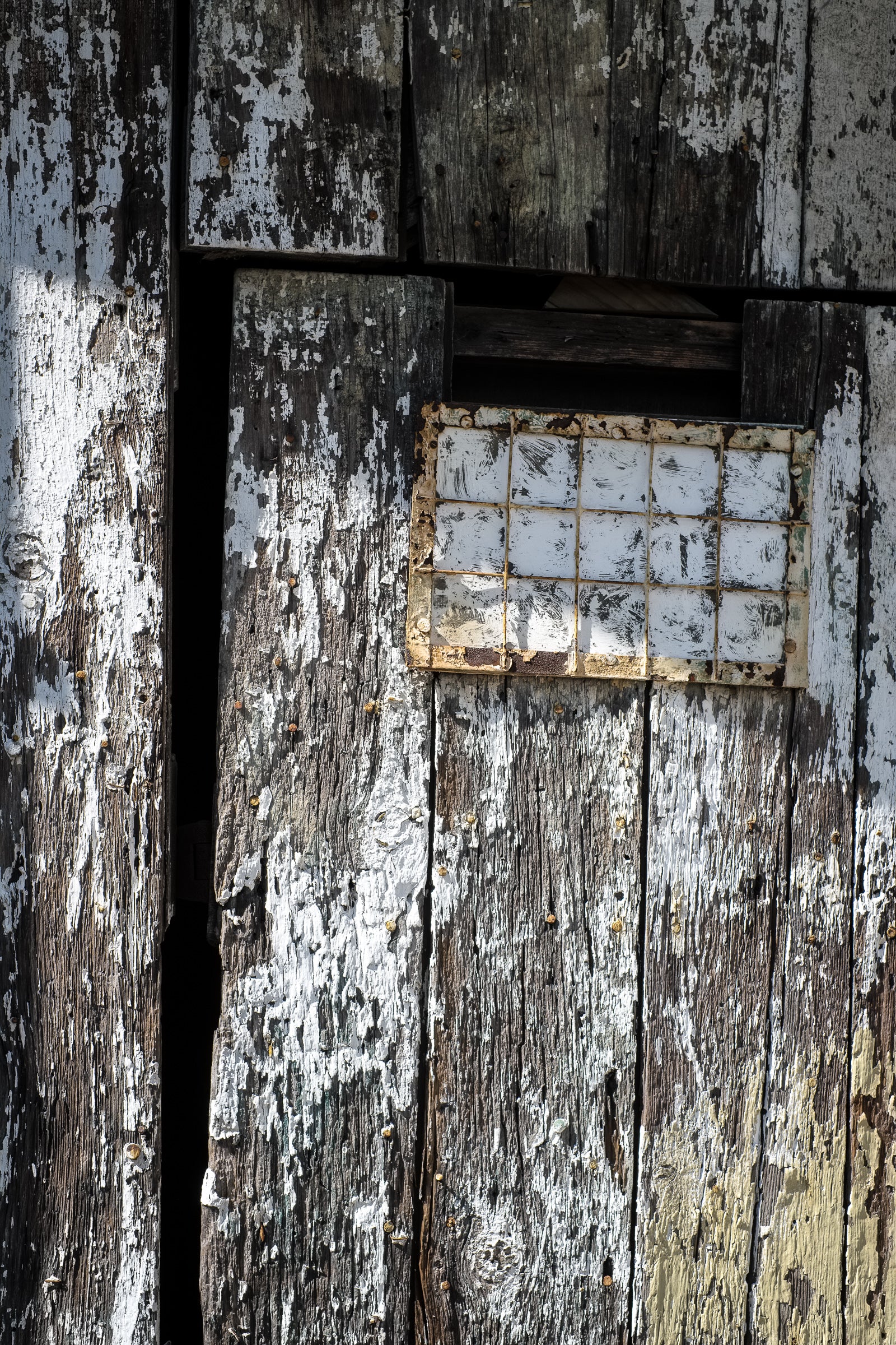 Ill-fitting wood door with small rectangular window that's been painted over; photographer Rick Graves