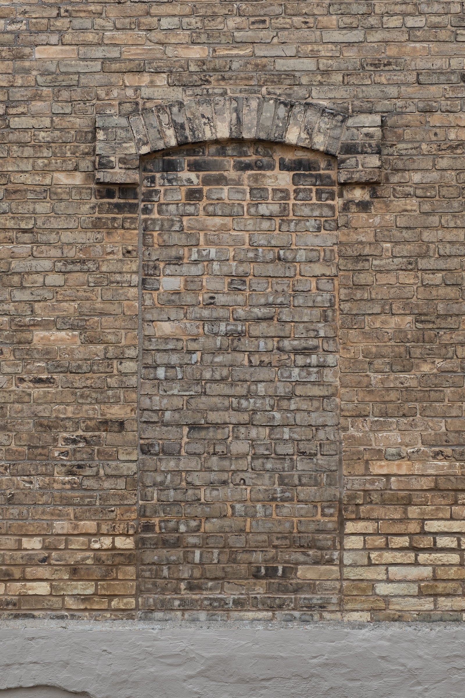 Brick wall with a decorative archway and bricked-in doorway; photographer Rick Graves