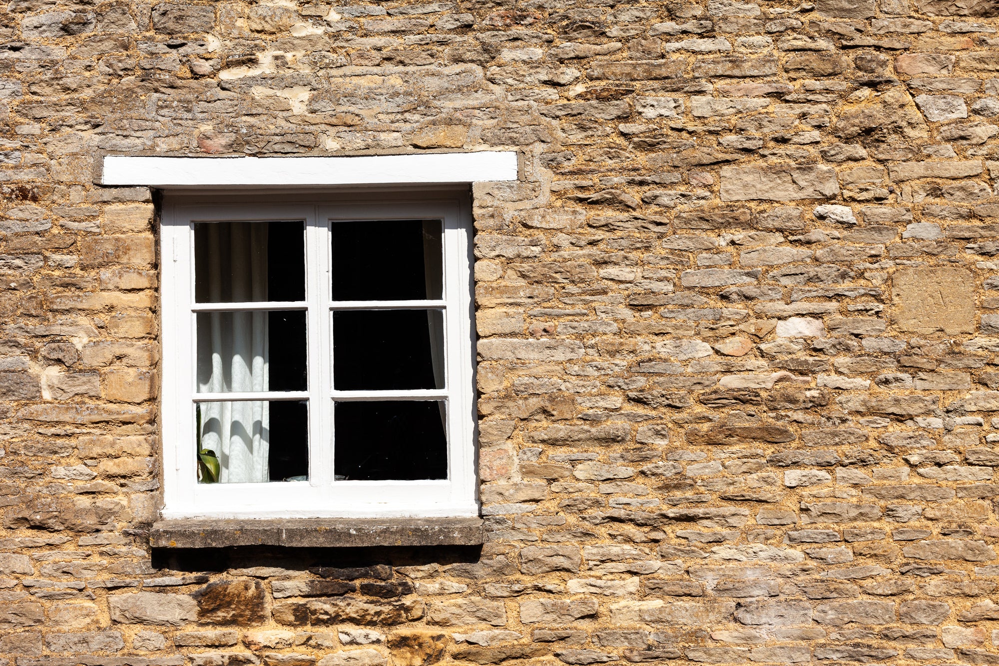 Sagging white window frame in a very old stone wall; photographer Rick Graves