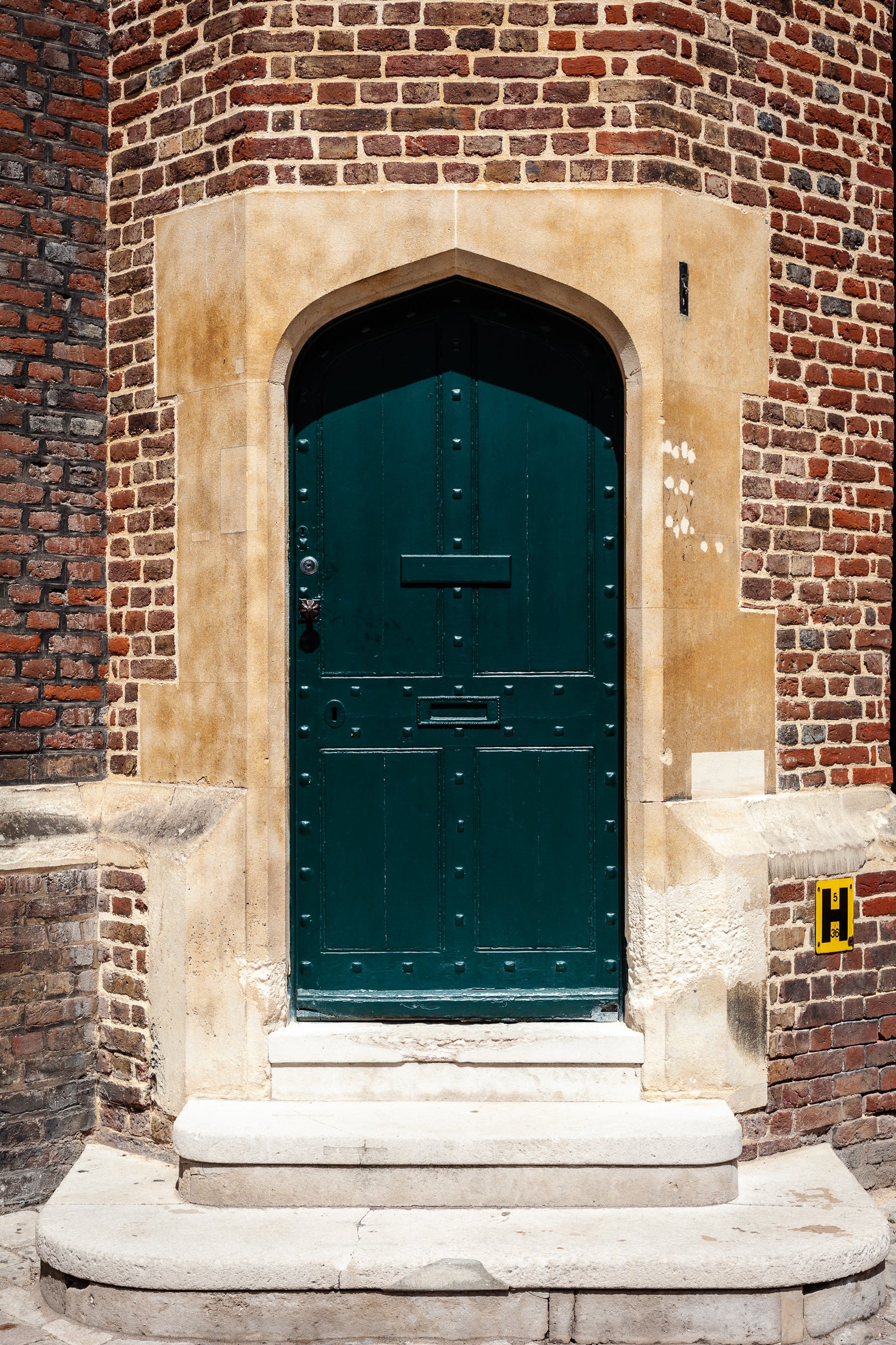 Green door set in a brick wall with stone archway; photographer Rick Graves