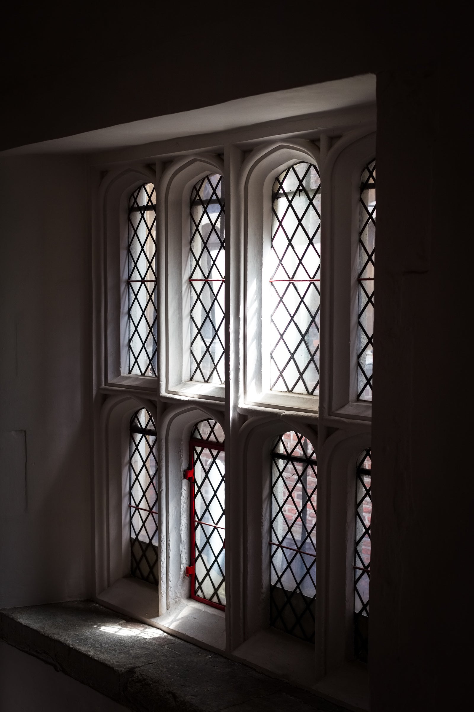 Arched leaded glass windows in a dark room; photographer Rick Graves