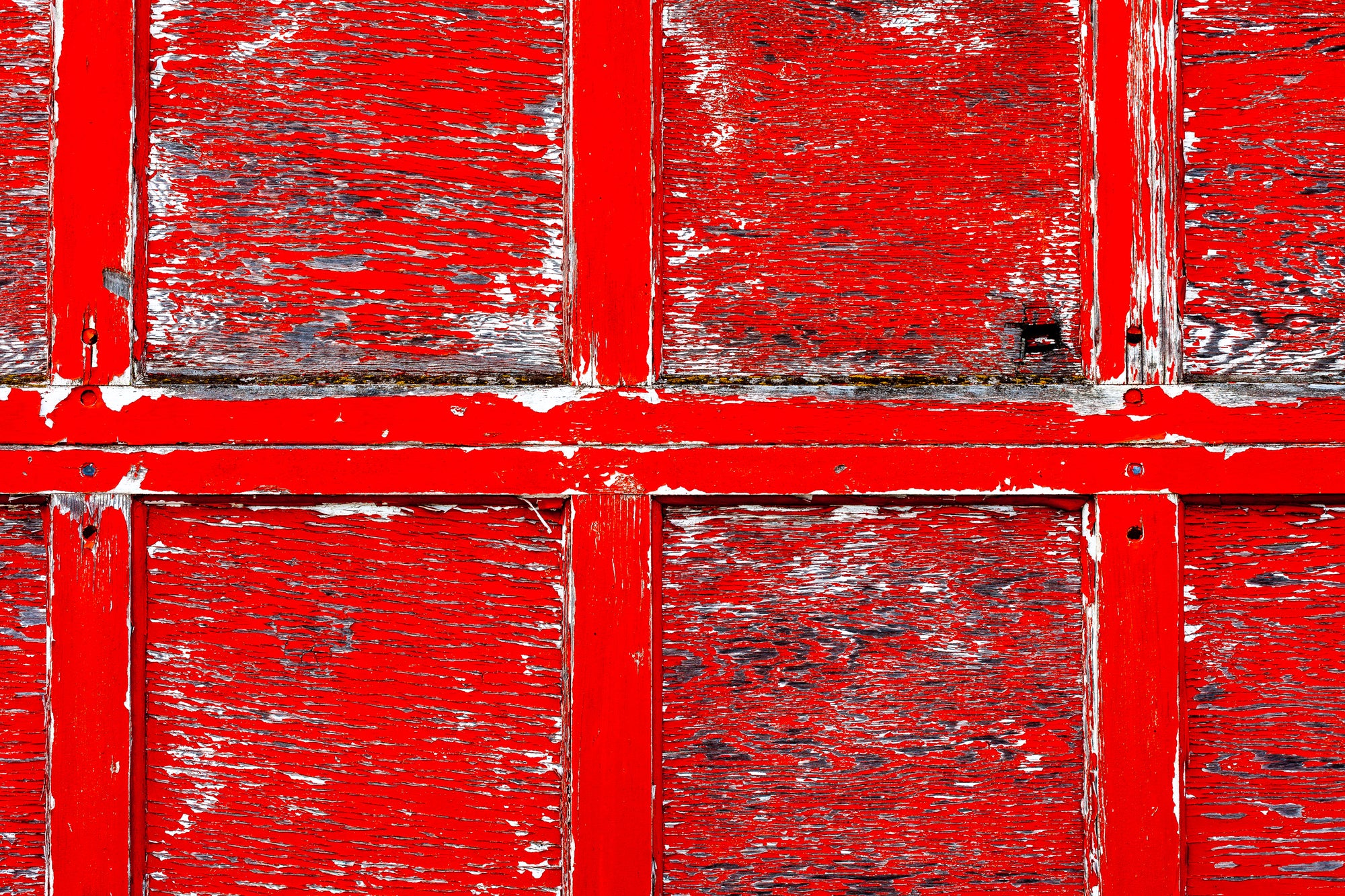 Close-up of a wood overhead door with peeling red paint paint; photographer Rick Graves