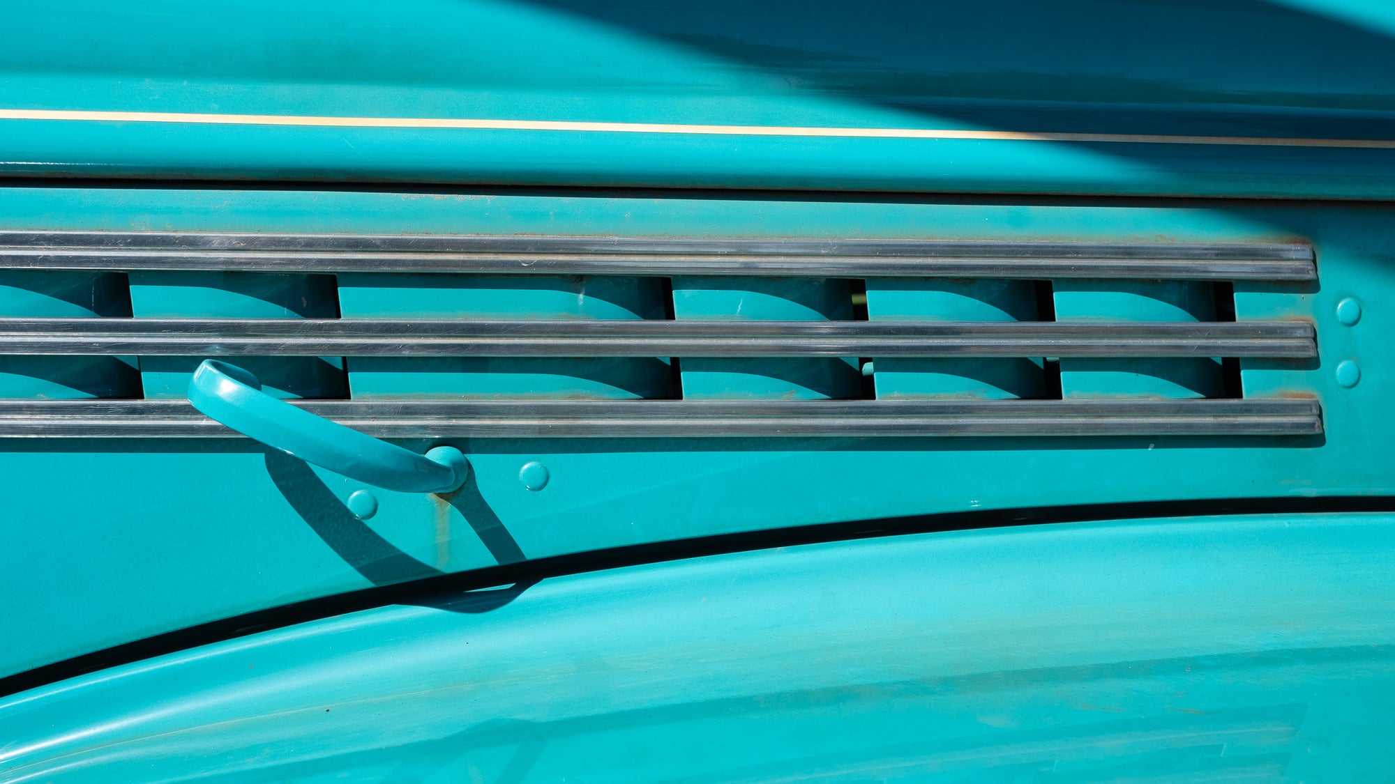 detail of shiny teal 1946 truck showing air vents and a handle