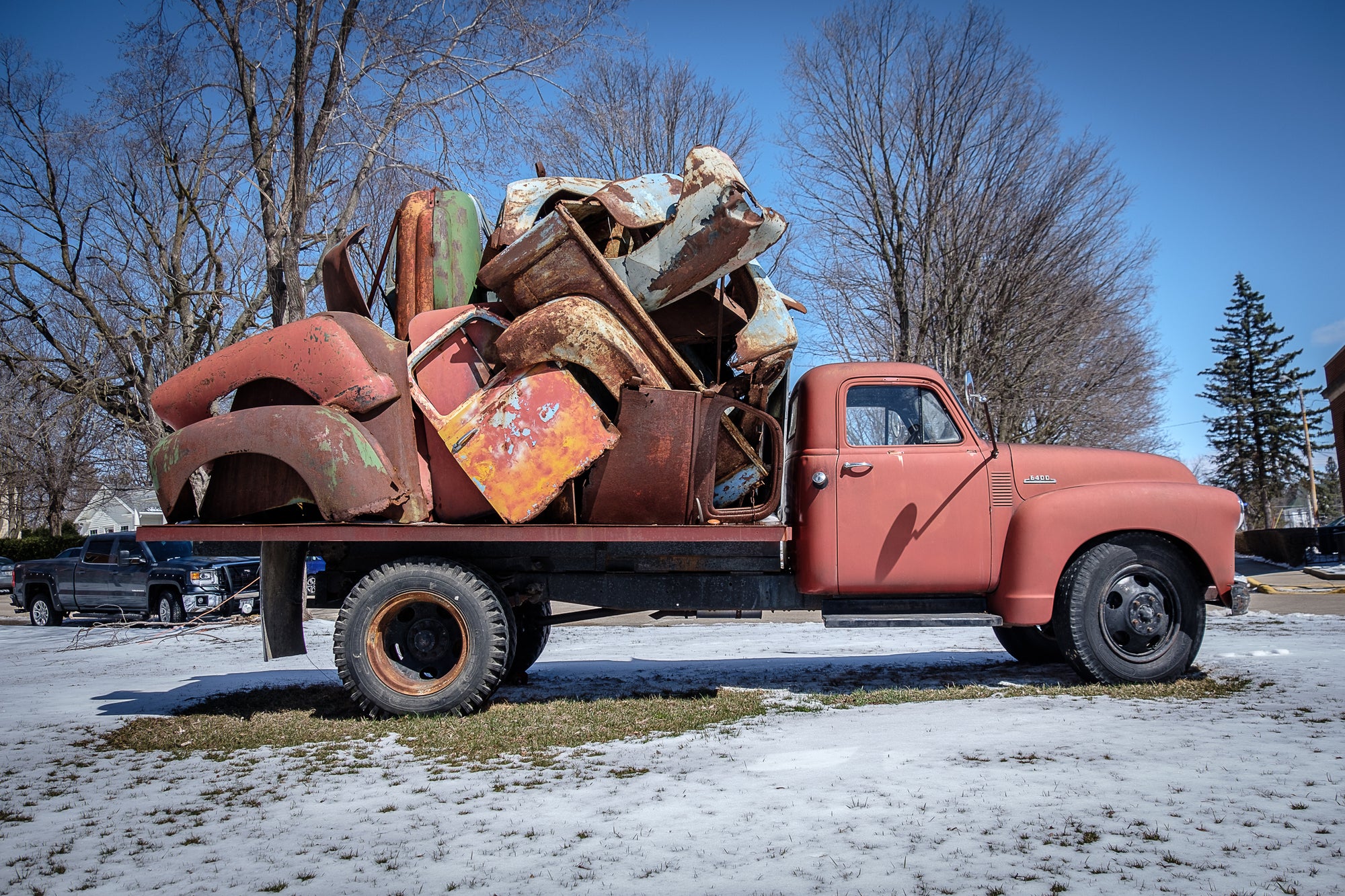 Passenger side of John Himmelfarb's 2015 truck sculpture REMAINS — an assemblage of rusty vehicle parts on the flatbed of a faded red 1953 Chevy; photographed, with permission, by Rick Graves