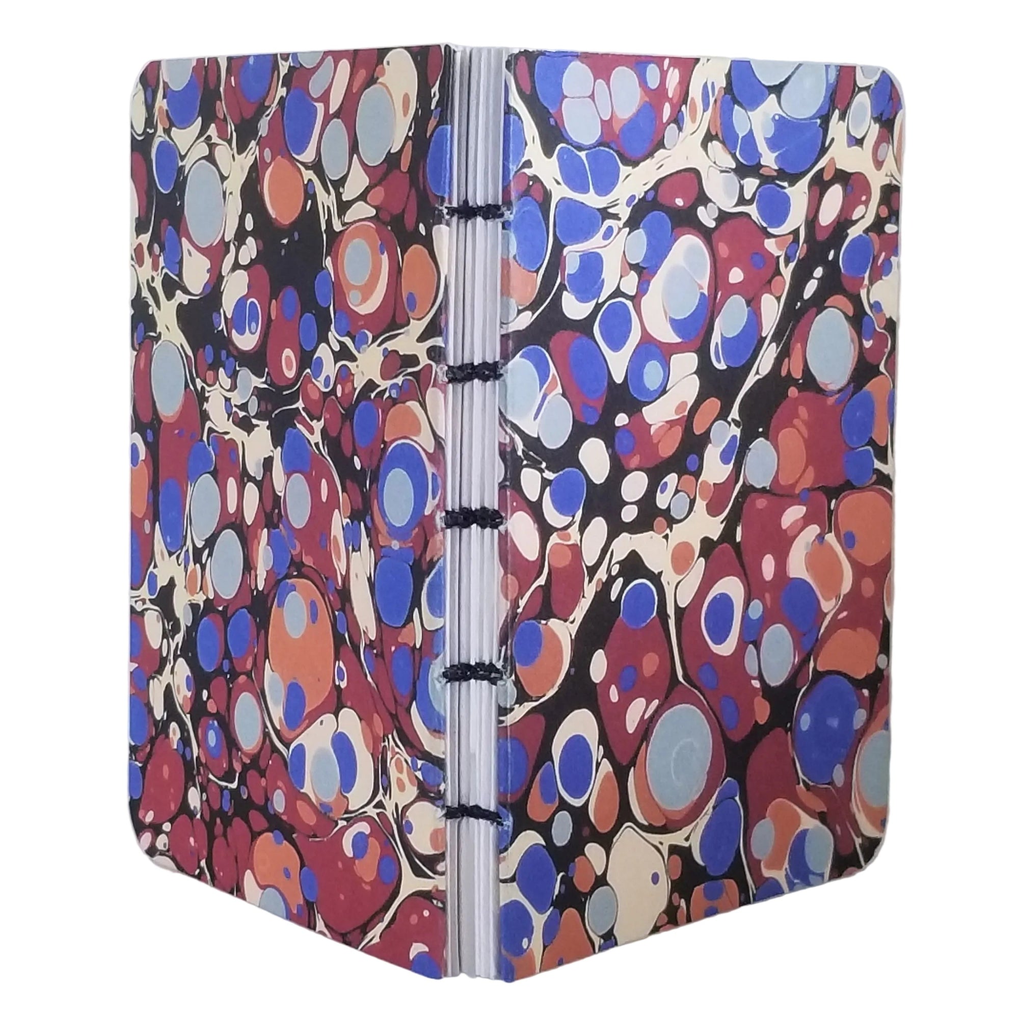 handmade small blank journal with predominantly blue and red printed marbling pattern, exposed spine, and bound with black waxed linen thread, ~4x5.5" 96 pages, shown on a white background