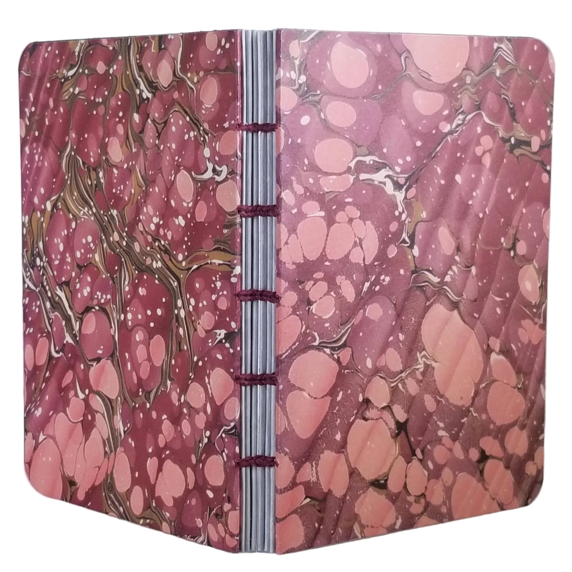 handmade coptic-bound blank notebook with multicolor printed marbled covers in dusty reds and rose, bound with magenta waxed linen thread, ~4x5.5" 96 pages, shown on a white background